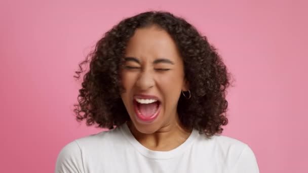Emotionele Afrikaanse dame schreeuwen uiten woede en glimlachen, roze achtergrond — Stockvideo