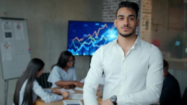 Jonge man uit het Midden-Oosten witte boorden werknemer glimlachend naar camera, poseren met gekruiste handen in het kantoor met collega 's — Stockvideo