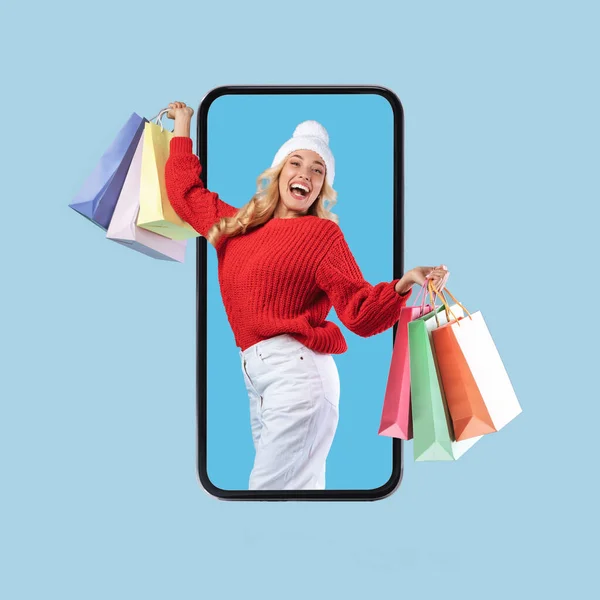 Cep telefonu ekranından alışveriş torbalarıyla bakan heyecanlı bir kadın. — Stok fotoğraf