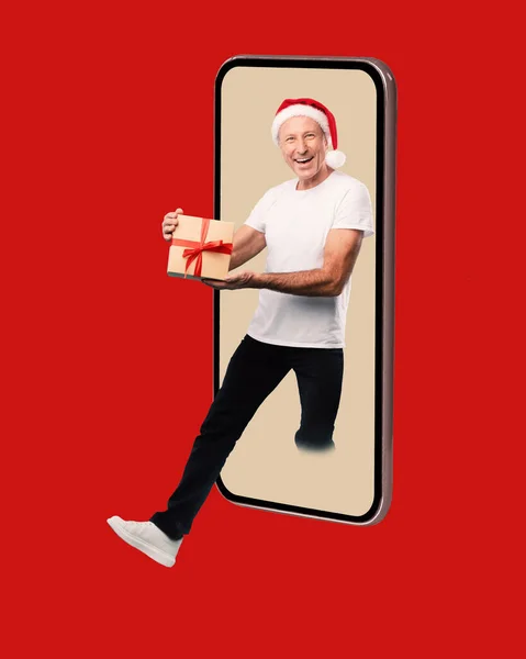 Homme mûr donnant le cadeau de Noël sortant écran cellulaire — Photo