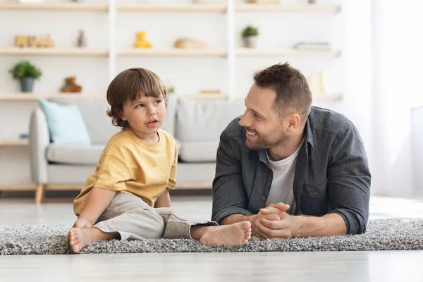 Οικογενειακή επικοινωνία. Νεαρός στοργικός πατέρας ακούει τον μικρό του γιο, περνάει ελεύθερο χρόνο μαζί στο σπίτι. — Φωτογραφία Αρχείου