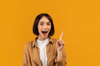 Vay canına, Evreka. Duygusal kadının harika bir fikri var, ilham buluyor, sarı arka planda ağzı açık poz veriyor.