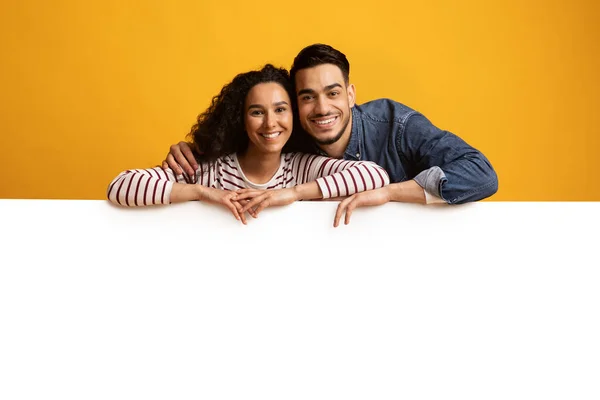 Feliz joven pareja de Oriente Medio se inclina en el tablero de anuncios grandes blancos — Foto de Stock