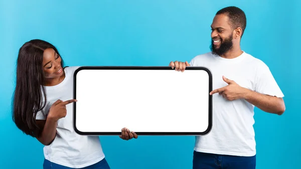 Ζευγάρι δείχνει σε μεγάλη λευκή άδεια οθόνη smartphone, μακέτα-up — Φωτογραφία Αρχείου