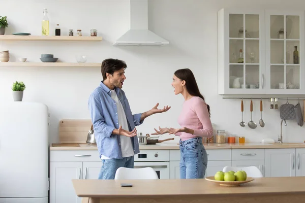 Enojada deprimida frustrada mujer europea milenaria jura por su marido molesto en el interior de la cocina — Foto de Stock