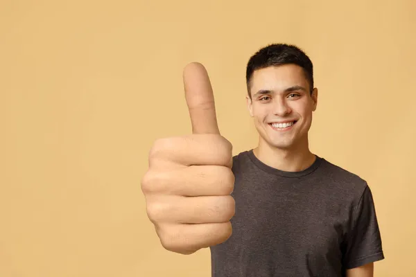 Guapo caucásico chico mostrando pulgar hacia arriba en beige — Foto de Stock