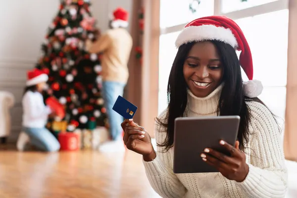 クリスマスオンラインショッピング。クレジットカードを示すタブレットを使用して笑顔の女性 — ストック写真