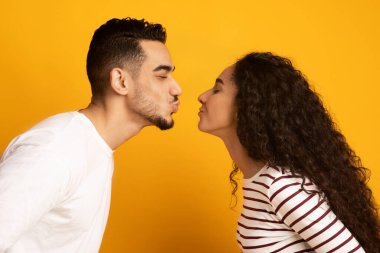 Neşeli genç Arap çift öpüşmeye hazır dudaklarıyla birbirlerine uzanıyorlar.