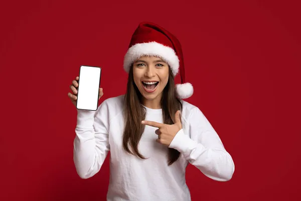 Increíble oferta. Hermosa mujer joven en Santa Sombrero Demostrando Smartphone en blanco — Foto de Stock