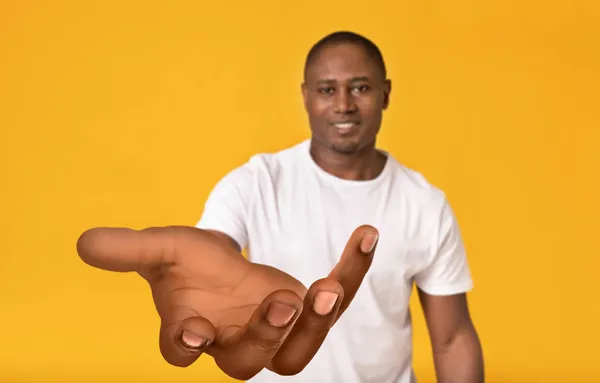 Smiling black guy stretching out his big hand, holding something, offering help, begging or reaching for something — Stock Photo, Image