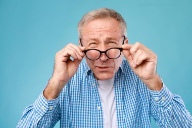 Mature man squinting wearing eyeglasses, looking at camera clipart