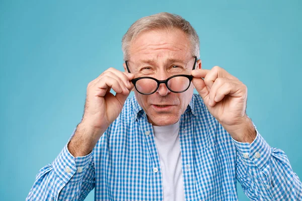 Mature man squinting wearing eyeglasses, looking at camera — Stock Photo, Image