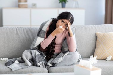 Hüsran yillik Hintli kadin peçetedeki burnunu siliyor ates, grip ve kanepede basagridan muzdarip.