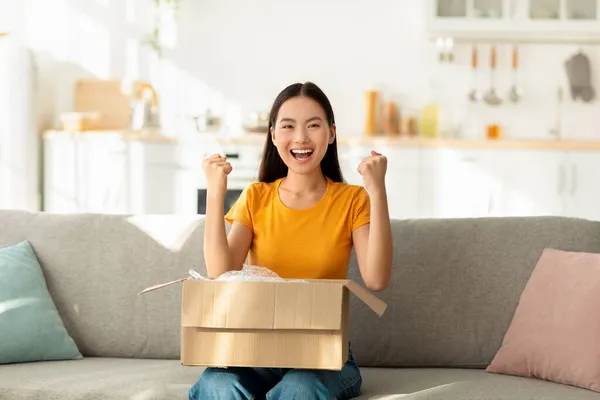 Nadšený asijské žena odbalení lepenkové krabice balíček, emocionálně reagovat na úspěšné nakupování, volný prostor — Stock fotografie