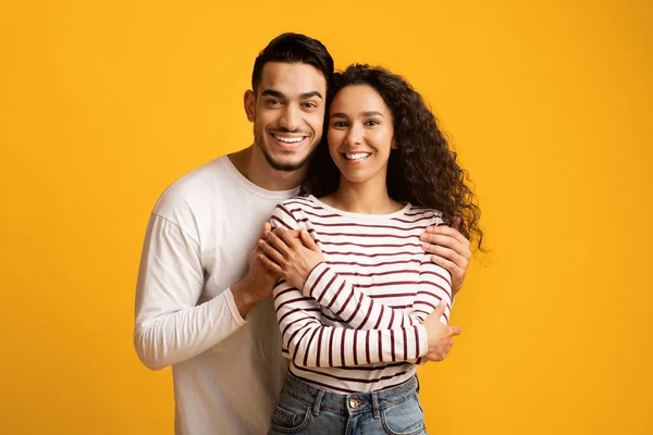 Porträtt av lycklig älskande Mellanösternpar Posing tillsammans över gul bakgrund — Stockfoto