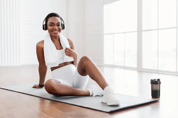 Γυμναστική μαύρη κυρία ακούγοντας μουσική κατά τη διάρκεια του διαλείμματος προπόνηση — Φωτογραφία Αρχείου