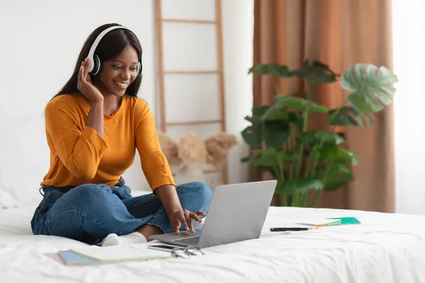 Afrykańska dama za pomocą laptopa i słuchawek Wideo Połączenie w sypialni — Zdjęcie stockowe