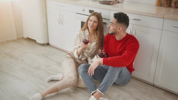 Huiselijke romantiek. jong gelukkig divers paar in liefde genieten van een bril van rode wijn en bespreken dagelijks nieuws — Stockvideo