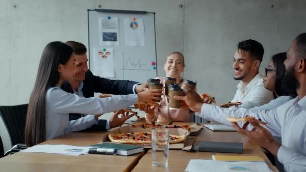 Позитивный деловой обед. Группа разнообразных коллег, болеющих за чашки кофе и поедающих пиццу во время встречи в офисе — стоковое видео