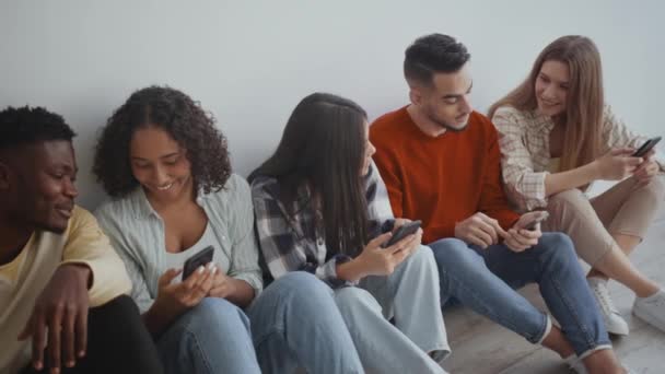 La comunicación de los jóvenes modernos. Grupo de jóvenes amigos alegres hablando juntos, compartiendo noticias sobre teléfonos inteligentes — Vídeo de stock