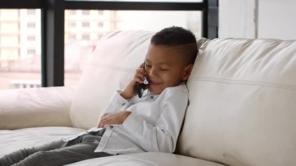 Vrolijke Preteen Black Boy praten op mobiele telefoon thuis — Stockvideo