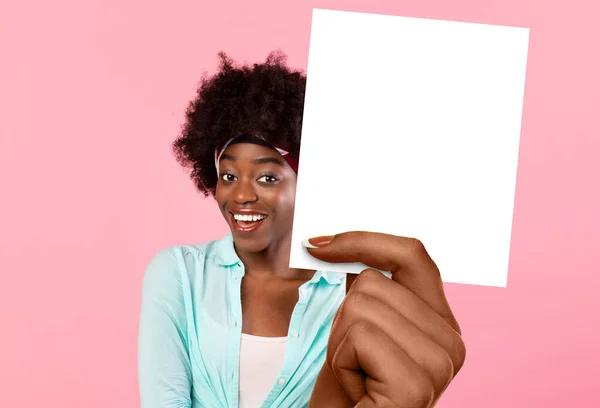 Afro-americano feminino segurando cartão em branco em pé sobre fundo rosa — Fotografia de Stock