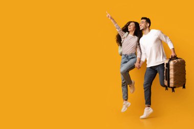 Sıcak Turlar. Bavulu atlayan ve işaret eden neşeli Arap çift