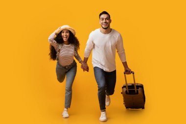 Tatile hazırım. Heyecanlı Arap Çifti Sarı Arkaplanda Koşarken