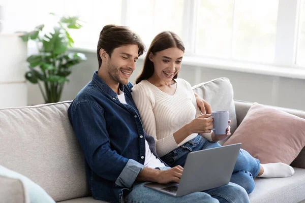 Alegre milenar marido e mulher europeus passar tempo livre e fim de semana juntos, olhando para laptop — Fotografia de Stock