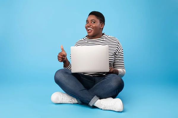 Dama afroamericana de gran tamaño usando pulgares de gestos para computadora portátil, fondo azul —  Fotos de Stock