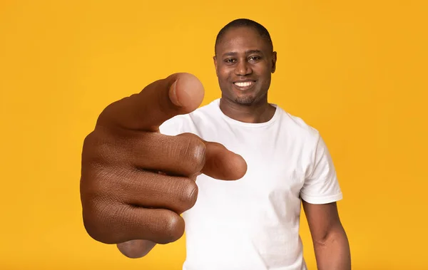 Счастливый взрослый афроамериканец, указывающий на камеру с большой рукой на фоне оранжевой студии — стоковое фото