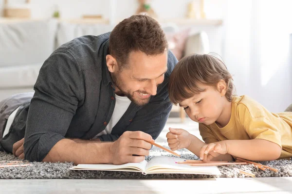Δημιουργική ανάπτυξη παιδιών. Κοντινό πορτρέτο του θετικού πατέρα ζωγραφίζει με το μικρό του γιο με πολύχρωμα μολύβια — Φωτογραφία Αρχείου