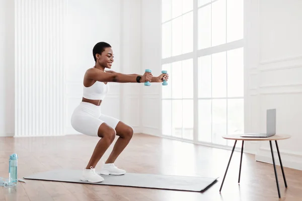 Joven mujer negra haciendo ejercicio con pesas delante de la computadora portátil —  Fotos de Stock