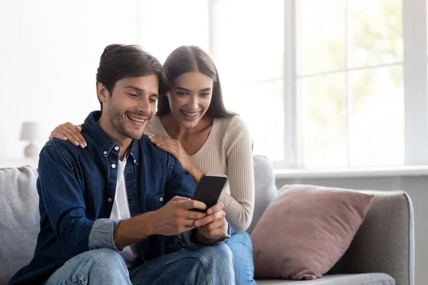 Usmívající se mladý běloch muž a žena dívající se na smartphone spolu, mít video hovor — Stock fotografie