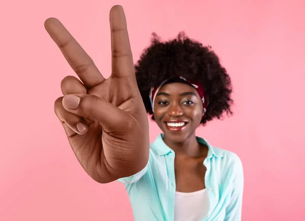 Feliz jovem mulher negra mostrando grande vitória v sinal no fundo do estúdio rosa — Fotografia de Stock