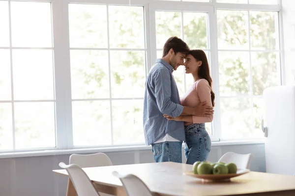 Satisfecho alegre joven marido y mujer bailando y abrazándose juntos en el interior de la cocina —  Fotos de Stock