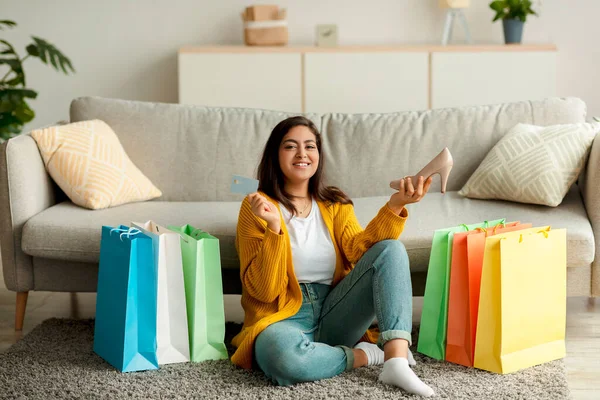 Kolay ödeme ve uzaktan alışveriş konsepti. Kredi kartı ve yeni ayakkabı taşıyan mutlu bir Arap kadın. — Stok fotoğraf