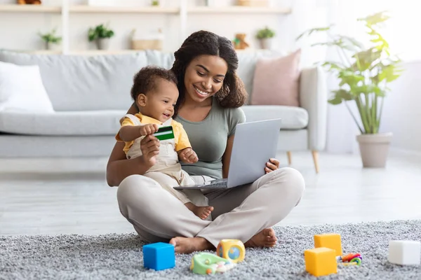 Черная мать с грудным ребенком использует топ для интернет-покупок на дому — стоковое фото