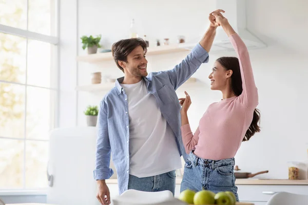 Feliz alegre atractivo joven marido y esposa bailando y divertirse juntos en el interior de la cocina —  Fotos de Stock