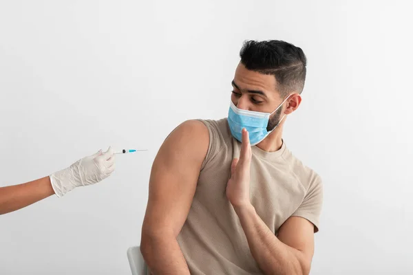 Hombre árabe joven en máscara desechable que impide que el médico haga la vacuna contra el coronavirus, estando en contra de la inmunización covid —  Fotos de Stock