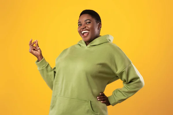 Radostné nadváha černá žena luskání prsty přes stojící žluté pozadí — Stock fotografie