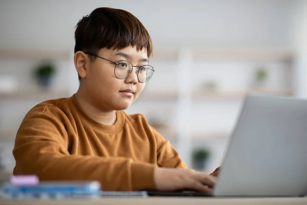 Inteligentny nastolatek siedzi przed laptopem, odrabiając lekcje — Zdjęcie stockowe