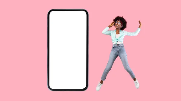 Mujer feliz mostrando blanco pantalla vacía del teléfono inteligente y saltar — Foto de Stock