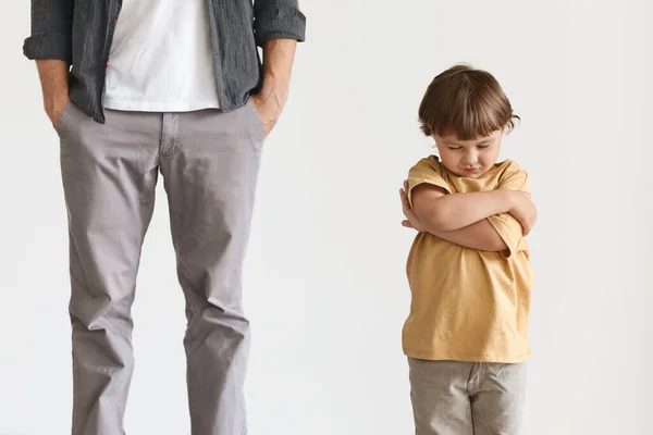 Beleidigter kleiner Junge mit verschränkten Händen, unkenntlich gemachter gleichgültiger Mann, der mit den Händen in den Taschen dasteht — Stockfoto