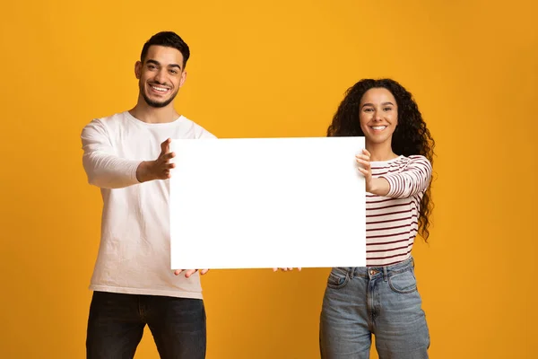 Werbebanner. Fröhliches junges arabisches Paar demonstriert weißes Blanko-Plakat — Stockfoto