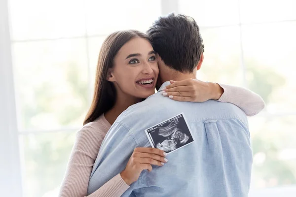 Boldog vidám millenniumi európai nő öleli férj és tartja ultrahang vizsgálat — Stock Fotó