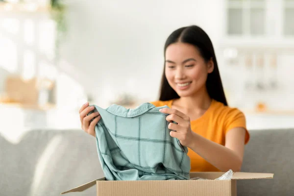 Comprar ropa por internet. Feliz joven asiático señora unboxing cartón entrega paquete después de compras en línea —  Fotos de Stock
