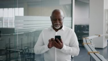 Gülümseyen Olgun Siyah İş Adamı İş Bulma Merkezi 'nde Yürürken Akıllı Telefonla Mesajlaşıyor