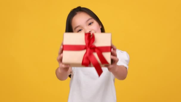 Trevlig helg. Liten asiatisk flicka ger presentförpackning till kameran, grattis och hälsning med säsongsbetonade festliga händelser — Stockvideo