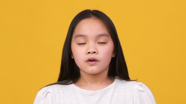 Aufrichtiger Kinderglaube. Nettes kleines asiatisches Mädchen betet zu Gott, macht Gebetsgeste mit geschlossenen Augen und schaut in die Kamera — Stockvideo